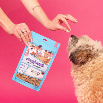 Donate a Bag Photo - a photo of a hand holding beef liver treats and the other hand feeding a dog a treat